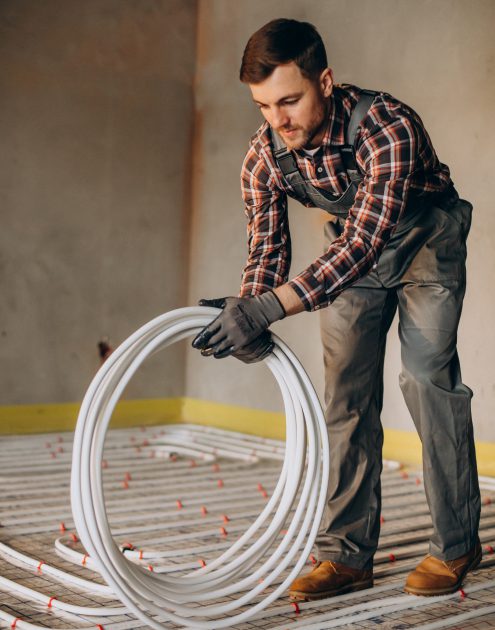 Service man instelling house heating system under the floor